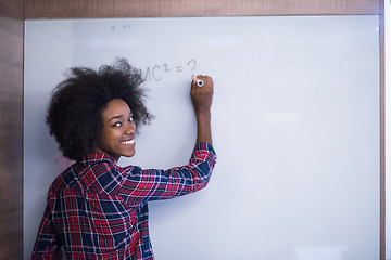 Image showing African American woman writing on a chalkboard in a modern offic