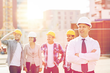 Image showing group of smiling builders in hardhats outdoors