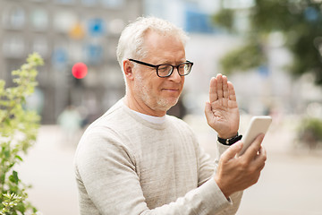 Image showing senior man having video call on smartphone in city