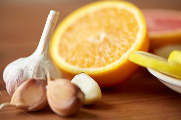 Image showing close up of garlic and orange on wooden table