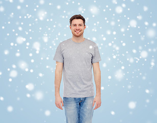 Image showing smiling young man in t-shirt and jeans over snow