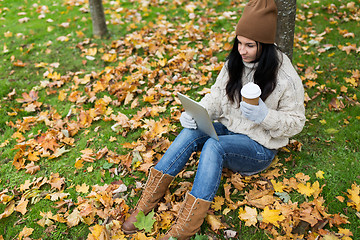 Image showing woman with tablet pc and coffee in autumn park