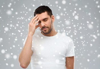 Image showing young man suffering from headache over snow