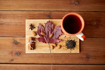 Image showing cup of tea, maple leaf and almond on wooden board