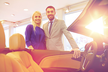 Image showing happy couple buying car in auto show or salon