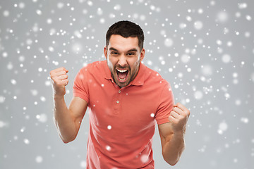 Image showing angry young man holding fists over snow