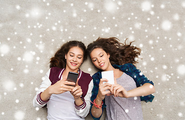 Image showing happy teenage girls lying on floor with smartphone