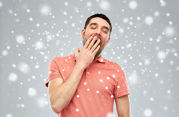 Image showing tired yawning man over snow background