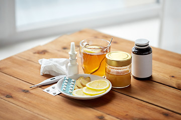 Image showing drugs, thermometer, honey and cup of tea on wood