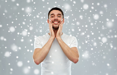 Image showing happy man applying aftershave or cream to face