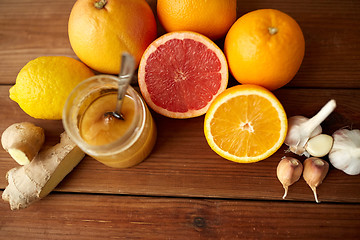 Image showing honey, citrus fruits, ginger and garlic on wood