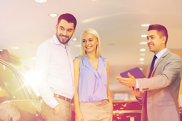 Image showing happy couple with car dealer in auto show or salon