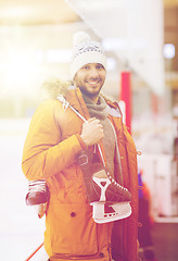 Image showing happy young man with ice-skates on skating rink