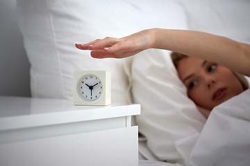 Image showing close up of woman with alarm clock in bed at home