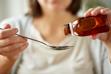 Image showing woman pouring medication from bottle to spoon