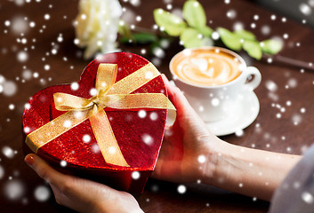 Image showing close up of hands holding heart shaped gift box