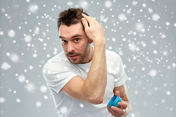 Image showing happy young man styling his hair with wax or gel