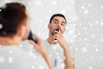 Image showing man shaving mustache with trimmer at bathroom