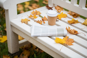 Image showing newspaper and coffee cup on bench in autumn park