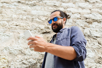 Image showing man texting message on smartphone at stone wall