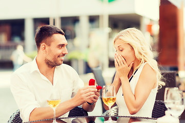 Image showing happy couple with engagement ring and wine at cafe