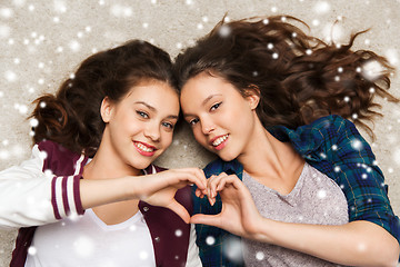 Image showing happy teenage girls lying on floor with heart