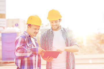 Image showing smiling builders in hardhats with tablet pc