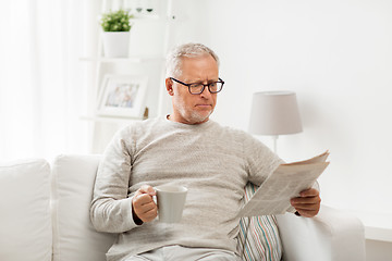 Image showing senior man in glasses reading newspaper at home