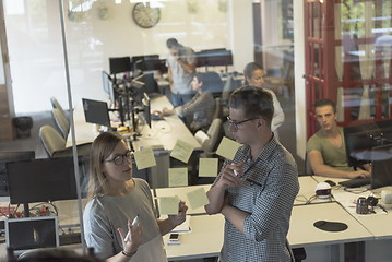 Image showing young couple at modern office interior writing notes on stickers