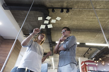 Image showing young couple at modern office interior writing notes on stickers