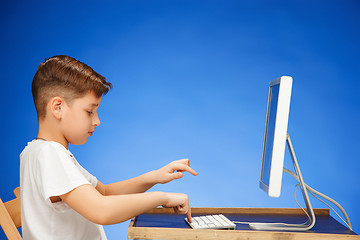 Image showing School-age boy sitting in front of the monitor laptop at studio