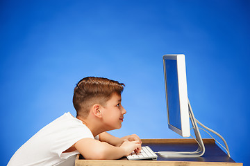 Image showing School-age boy sitting in front of the monitor laptop at studio