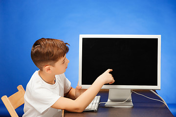 Image showing School-age boy sitting with the monitor laptop at studio