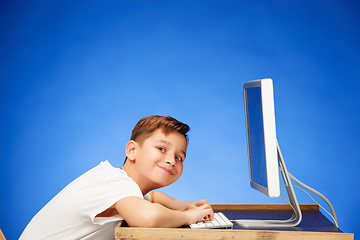 Image showing School-age boy sitting in front of the monitor laptop at studio