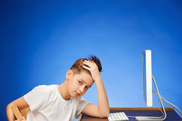 Image showing School-age boy sitting in front of the monitor laptop at studio