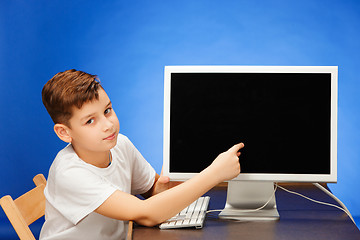 Image showing School-age boy sitting with the monitor laptop at studio