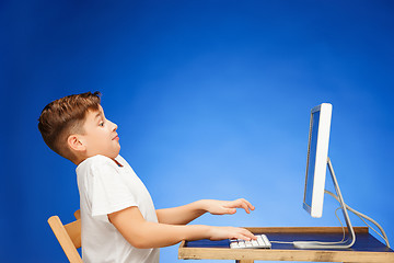 Image showing School-age boy sitting in front of the monitor laptop at studio