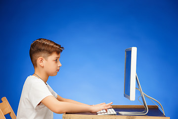 Image showing School-age boy sitting in front of the monitor laptop at studio