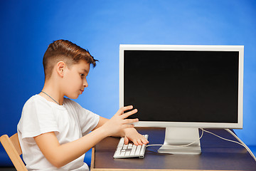 Image showing School-age boy sitting with the monitor laptop at studio