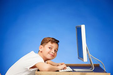 Image showing School-age boy sitting in front of the monitor laptop at studio
