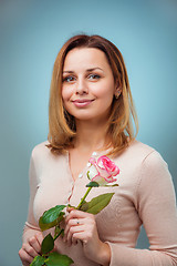 Image showing Young woman holding rose and smiling