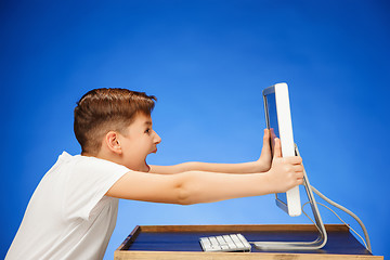 Image showing School-age boy sitting in front of the monitor laptop at studio