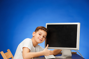 Image showing School-age boy sitting in front of the monitor laptop at studio