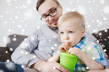 Image showing father and son drinking from cup at home