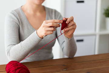 Image showing woman knitting with crochet hook and red yarn