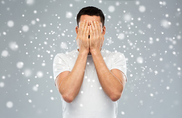 Image showing man covering his face with hands over snow