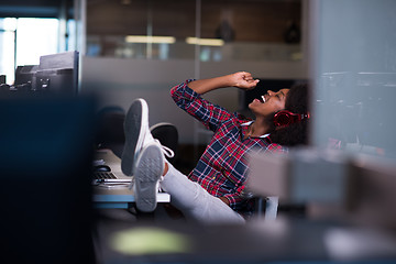 Image showing woman at her workplace in startup business office listening musi