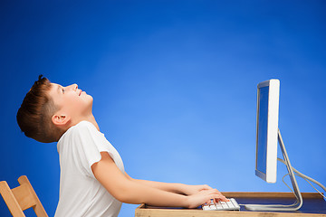 Image showing School-age boy sitting in front of the monitor laptop at studio