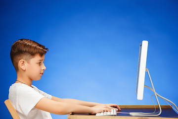 Image showing School-age boy sitting in front of the monitor laptop at studio