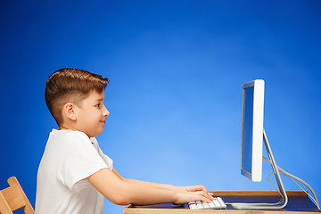 Image showing School-age boy sitting in front of the monitor laptop at studio